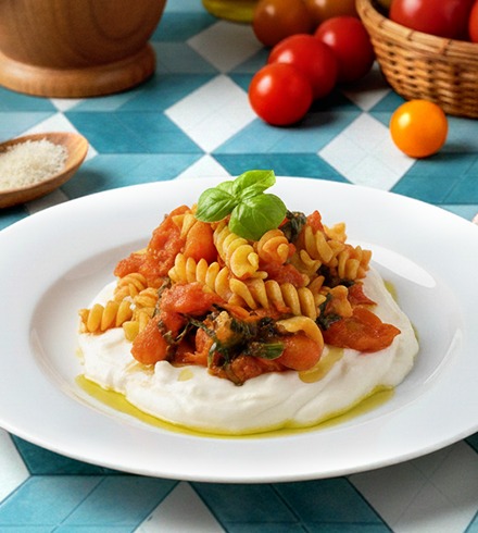 Fusilli tricolore con tomate y albahaca sobre ricotta en crema